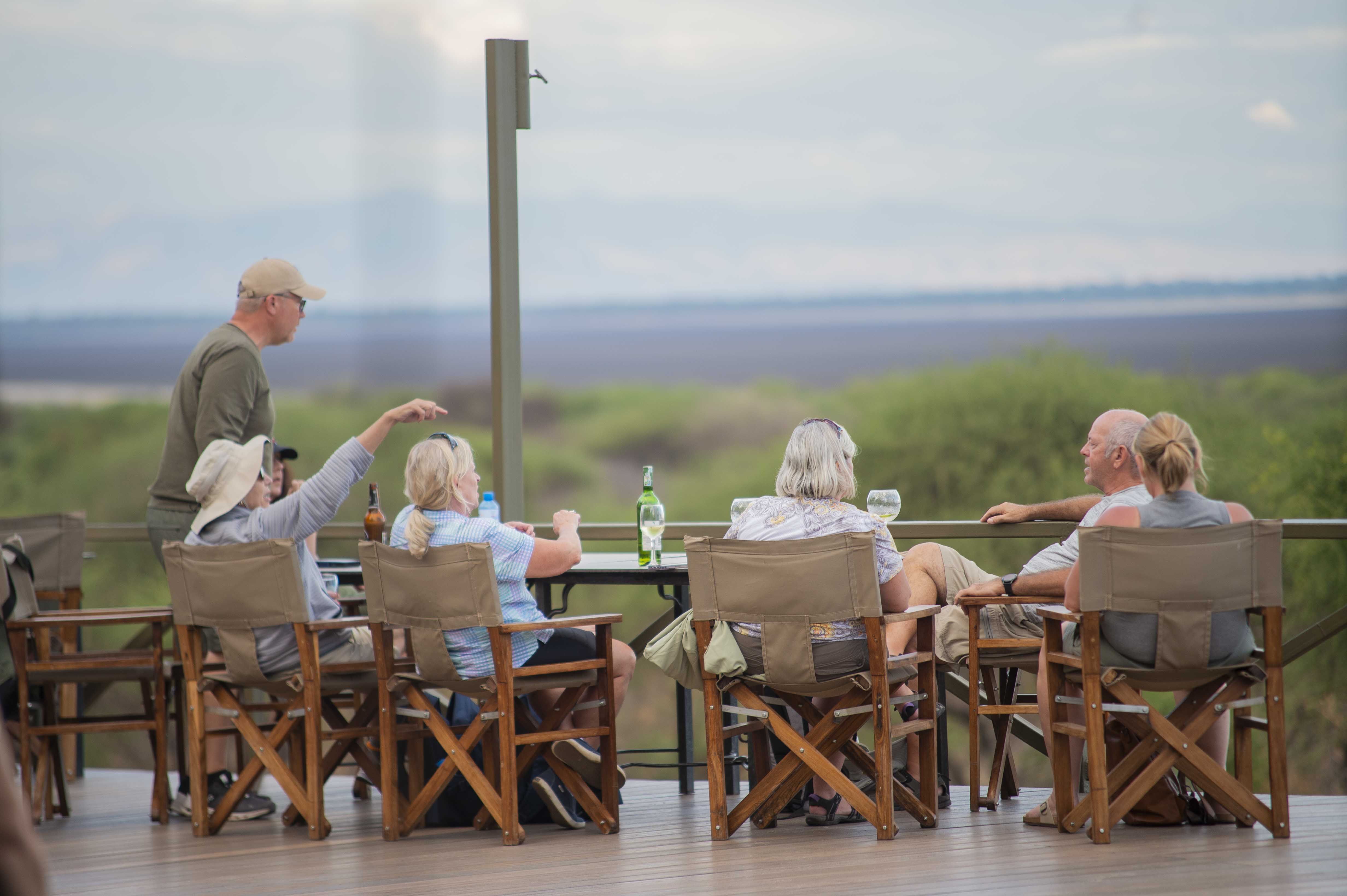 Guests relaxing on a lodge deck with a wide Tanzania view