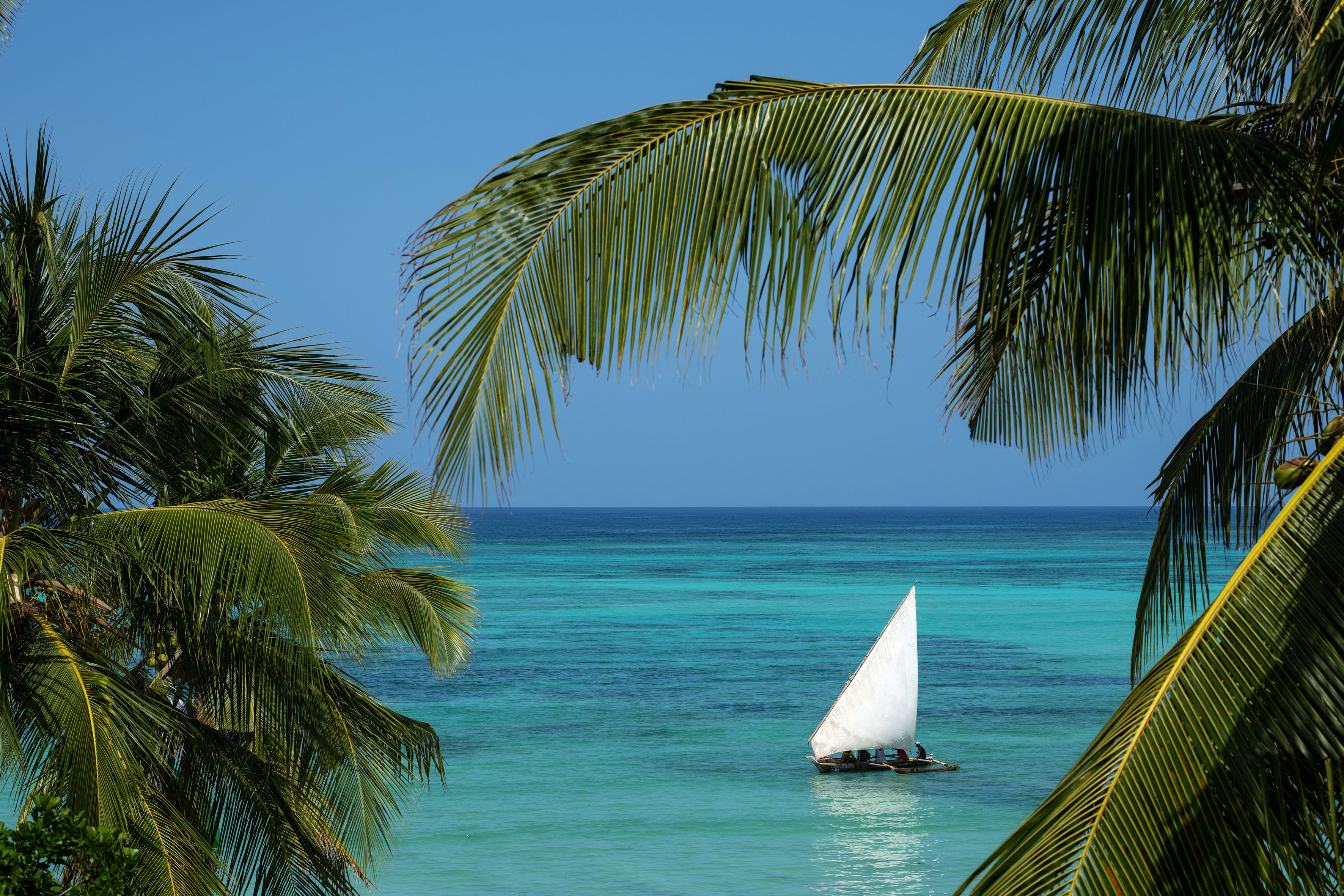 A dhow on a white-sand Zanzibar beach beside turquoise water
